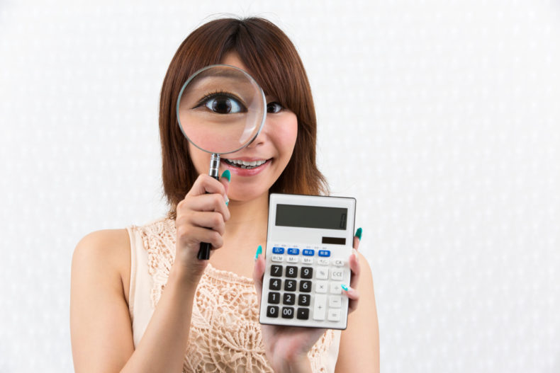 虫めがね・電卓を持つ女性